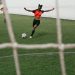 girl in red shirt and black shorts kicking a soccer ball